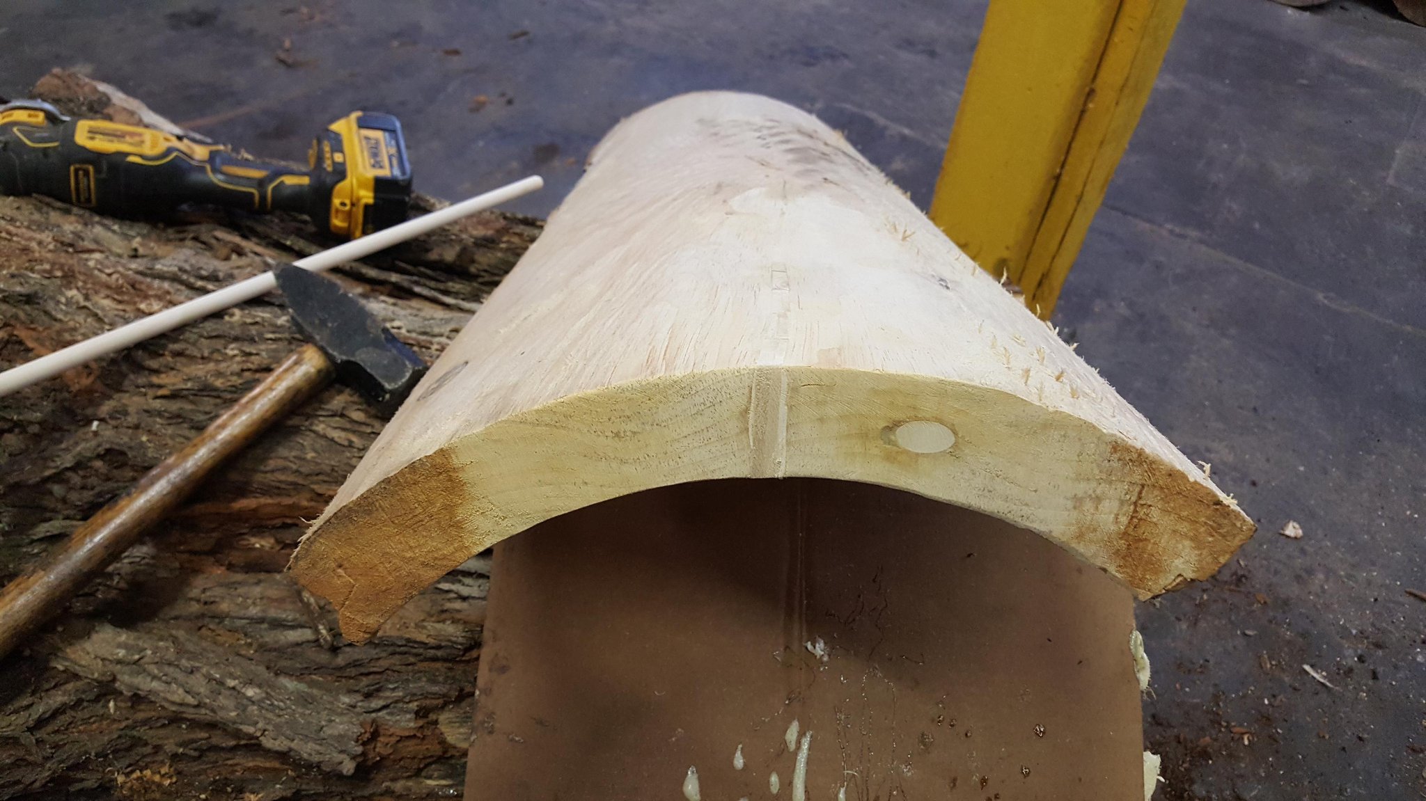 IC WOOD half-log after wood filler applied and sanded — crack nearly invisible, smooth pale wood surface, repair complete, DeWalt oscillating tool visible in background